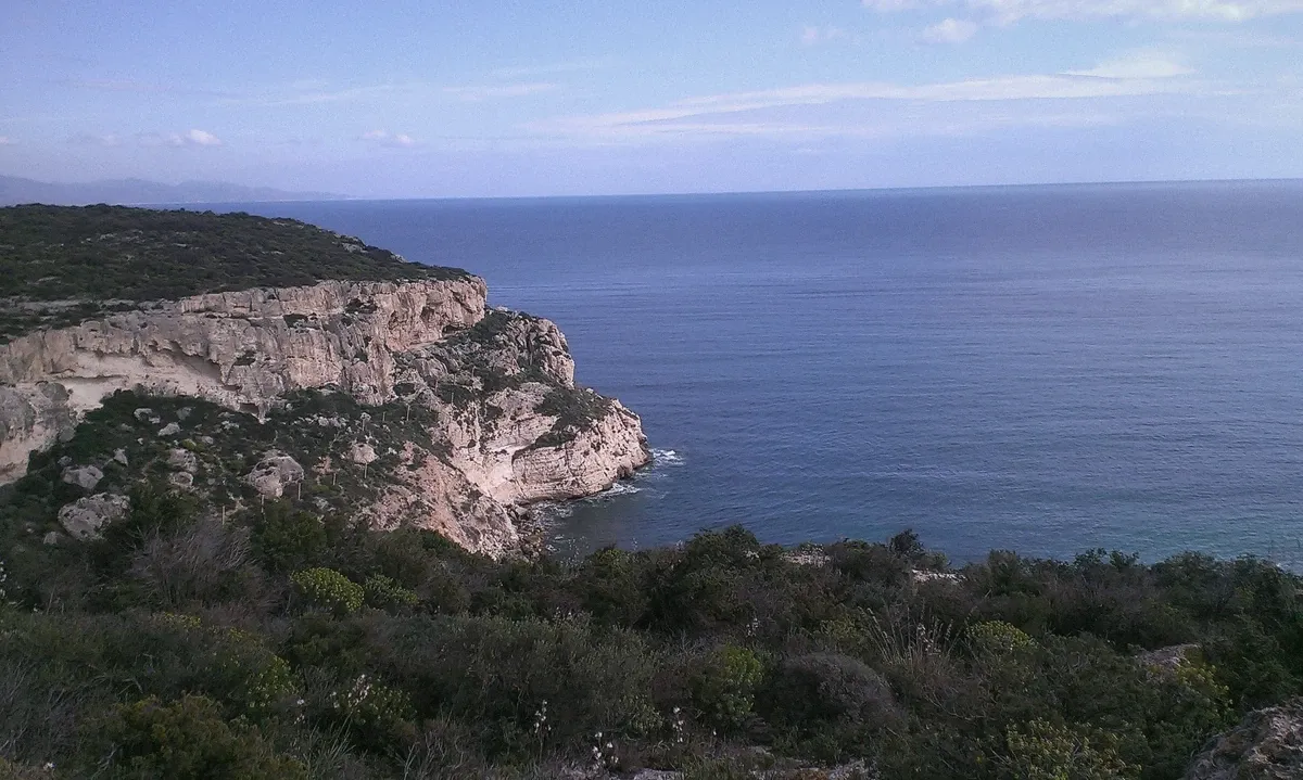 Cala Fighera hidden cove with limestone cliffs and clear water, a swim stop on the Nautisardinia Cagliari boat tour