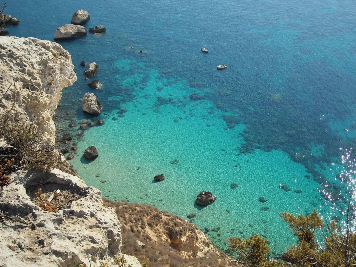 Limestone cliffs of Capo Sant'Elia under the Sella del Diavolo above clear water on the Nautisardinia Cagliari boat tour route